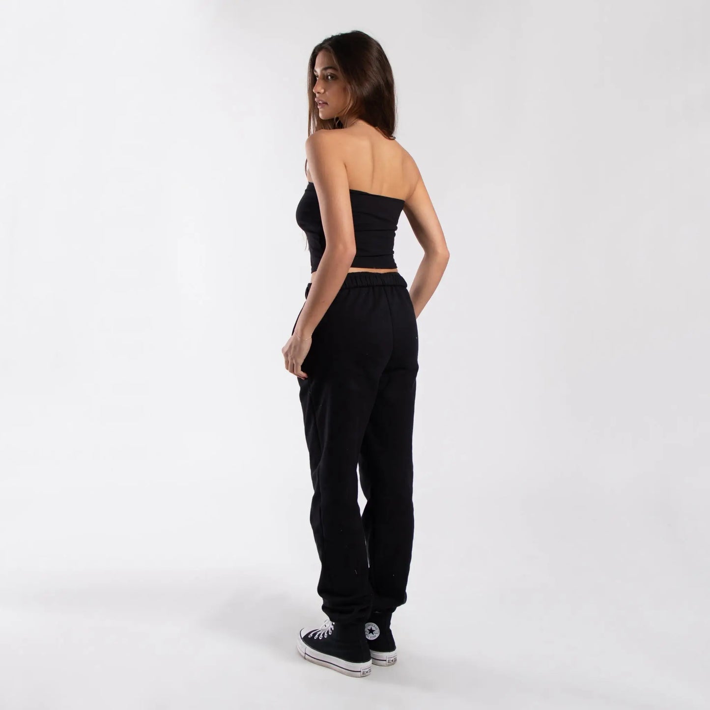 Black strapless crop top with matching jogger pants and Converse sneakers for women