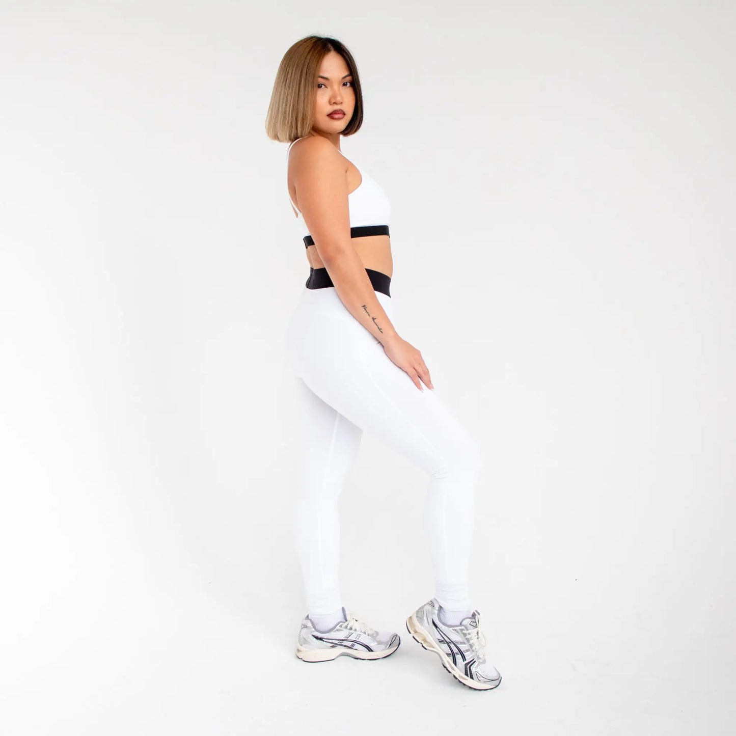 White athletic leggings with black waistband and silver sneakers from 1000BD info otlapparel