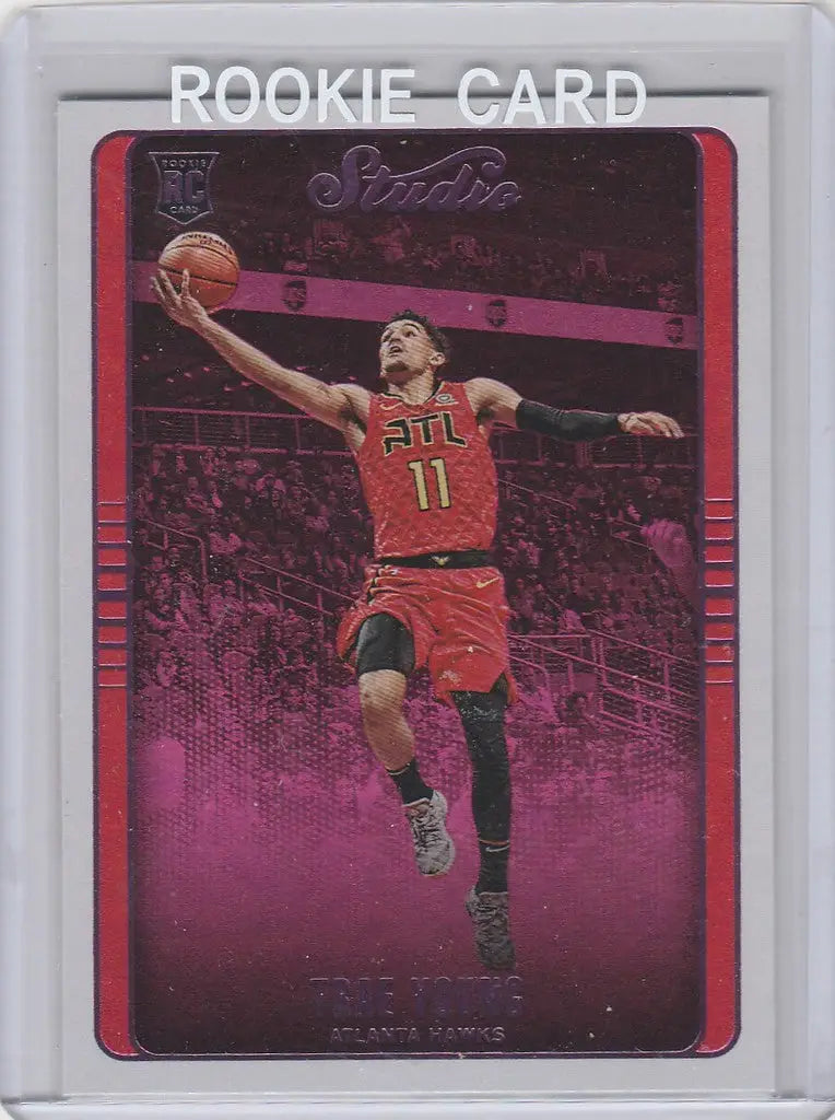 Basketball rookie card of Trae Young laying up in red jersey number 11 from Chronicles Trae