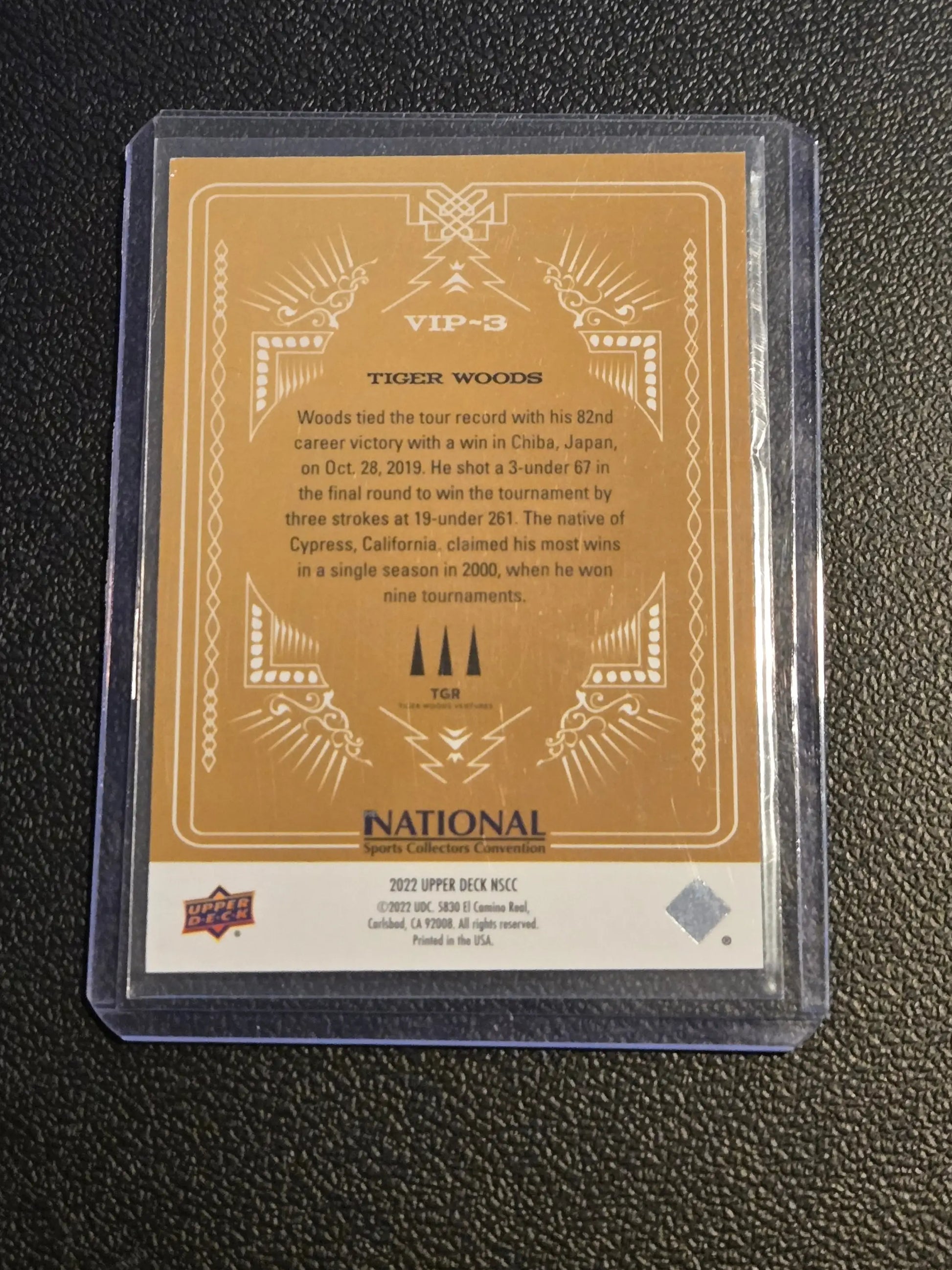 Gold-colored Tiger Woods sports trading card in clear sleeve from 2022 Upper Deck National Sports Collectors Convention