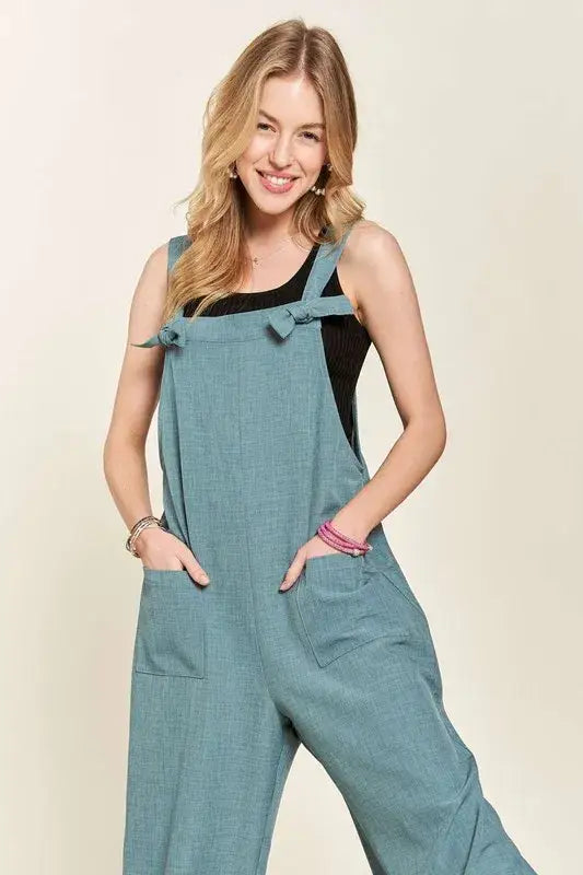 Young woman modeling ADORA Knotted Wide Strap Wide Leg Overalls with front pockets