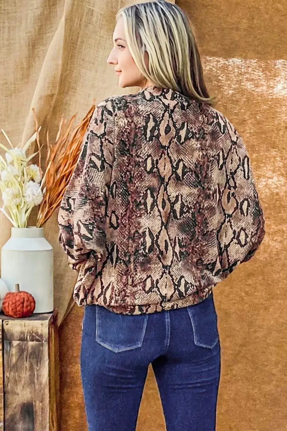 Woman wearing a Snake Print Choker Neck Dolman Sleeve Top with blue jeans