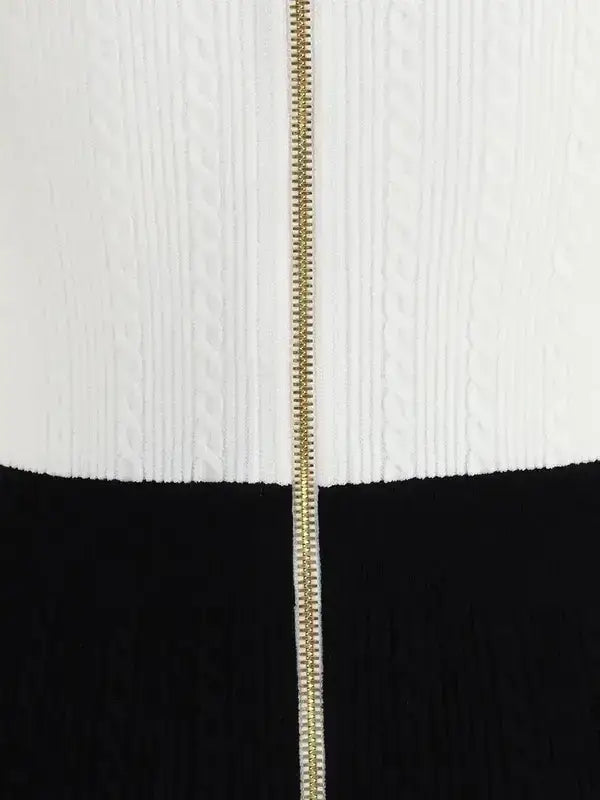 White cable-knit sweater with gold zipper paired with black skirt or trousers for braided pattern midi dress