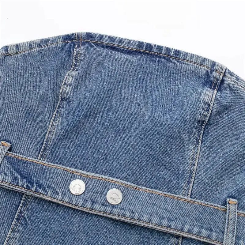 Close-up of light blue denim fabric with stitching and silver buttons on a blue denim corset top