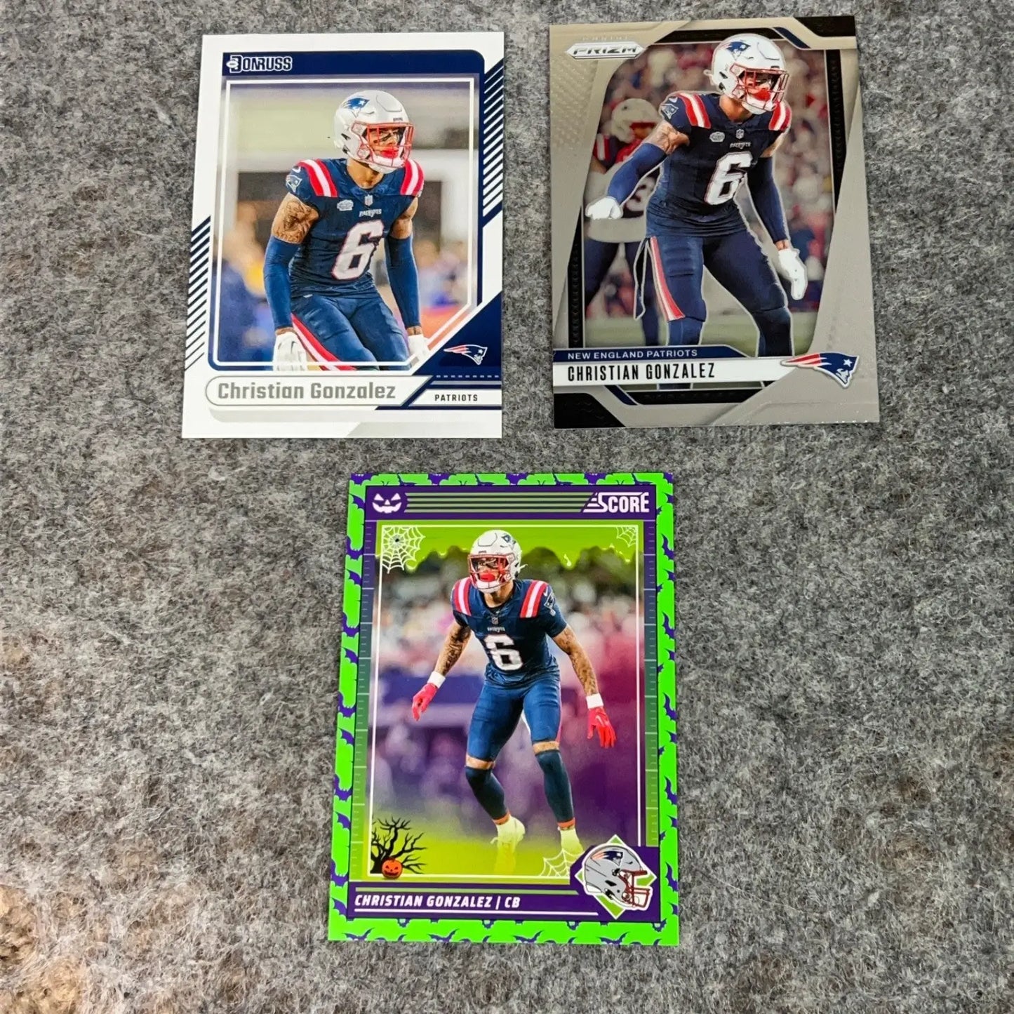 Three Christian Gonzalez New England Patriots 2024 NFL football trading cards displayed