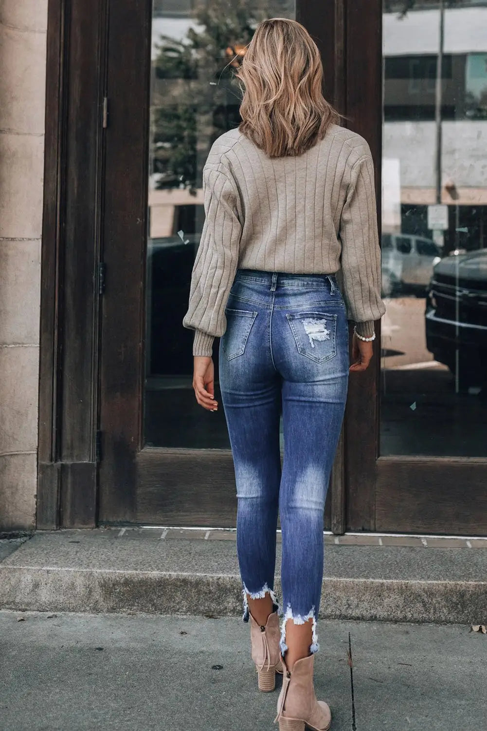 Woman from behind in beige ribbed sweater and Dark Blue Washed Distressed Slits Skinny Jeans