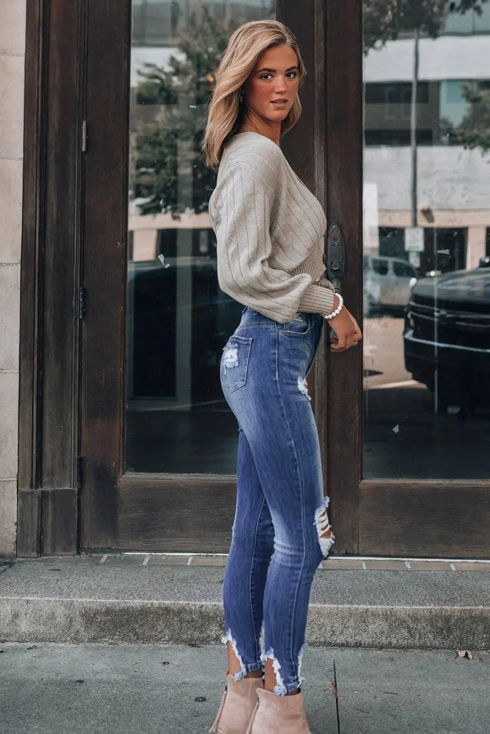 Woman wearing light brown cable-knit sweater and Dark Blue Washed Distressed Slits Skinny Jeans