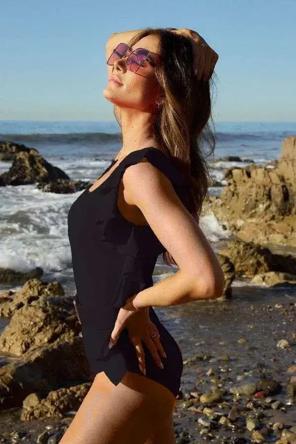 Black one-piece swimsuit with shoulder ruffle, cutout design, and high neckline