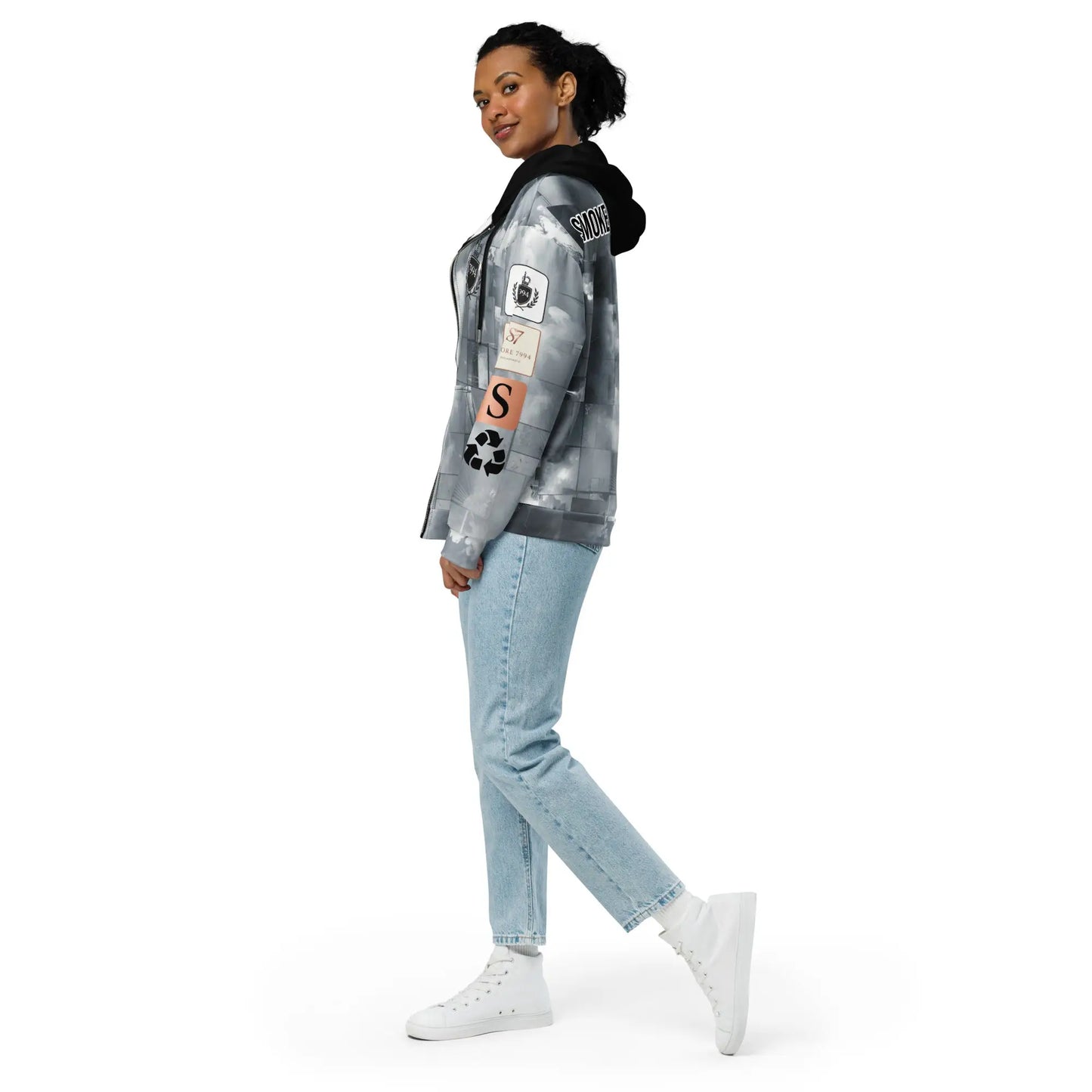 Woman wearing gray tie-dye exit illusion hoodie with patches, light blue jeans, white high-tops