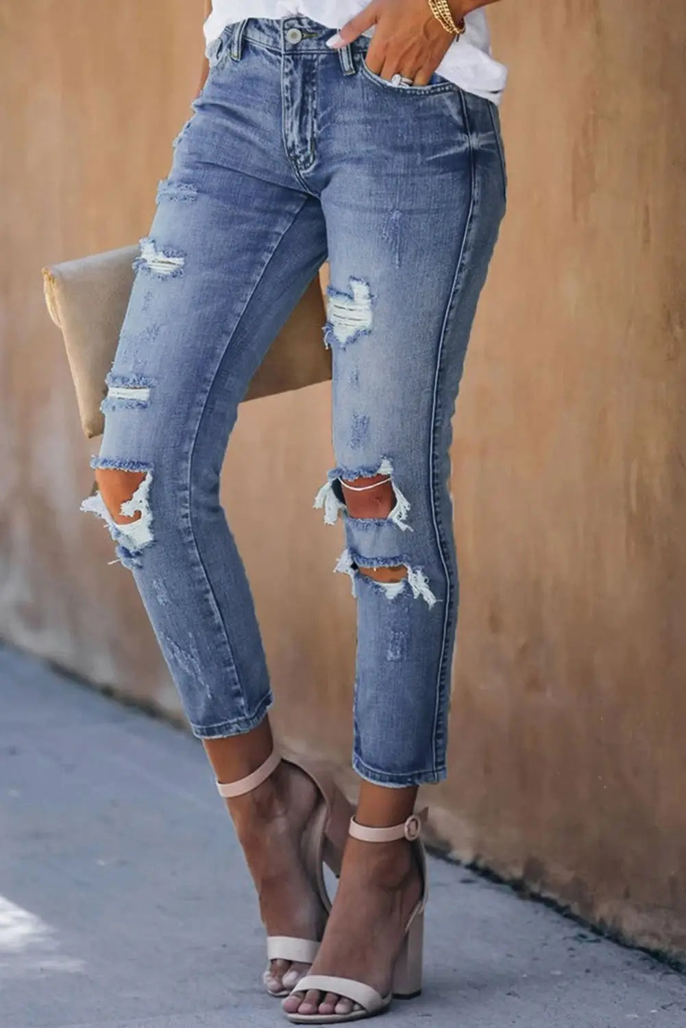 Fading distressed holes on light wash blue distressed skinny crop jeans with ripped knees