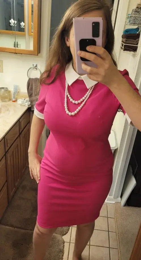 Woman in a hot pink sheath dress with white collar cuffs and double-strand pearls