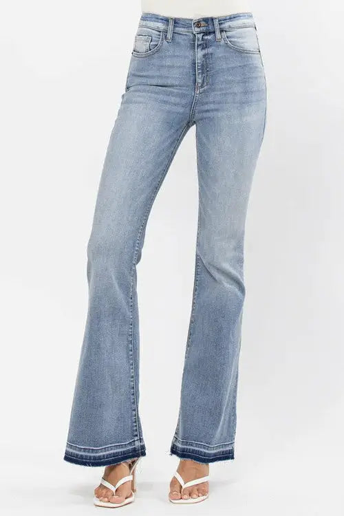 Light wash high rise flare jeans with raw cut hem and frayed hems paired with white sandals