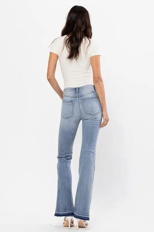 Woman from back in high rise flare jeans with raw cut hem and bottom detail