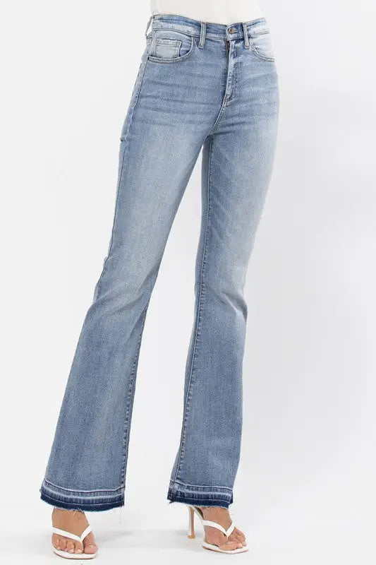 Light wash blue denim high rise flare jeans with raw cut hem and distressed details