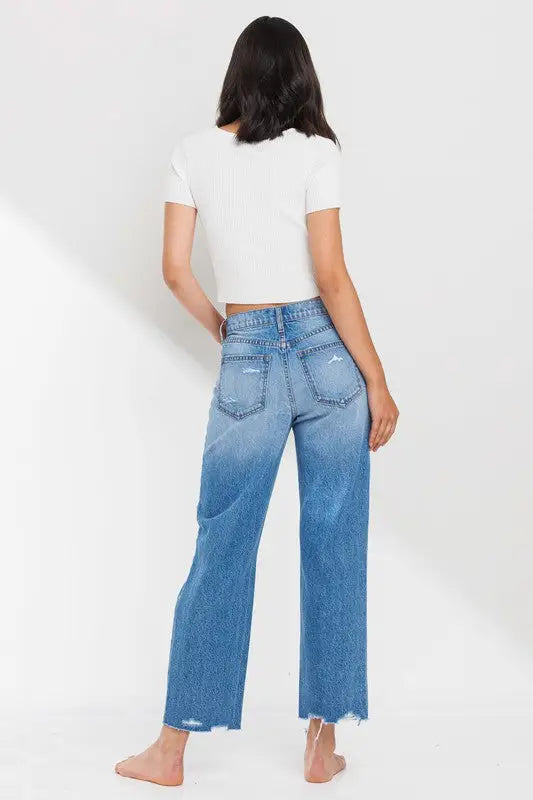 Women’s high rise straight leg distressed denim jeans with raw hem and faded wash