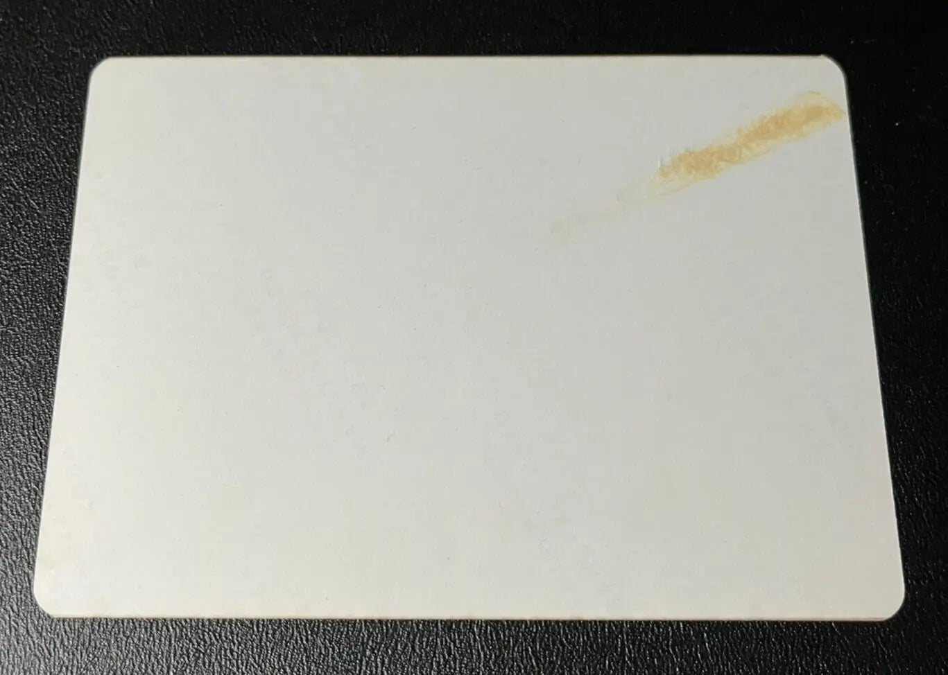 Rectangular white baseball card with rounded corners and a stain featuring Joe DiMaggio Yankees