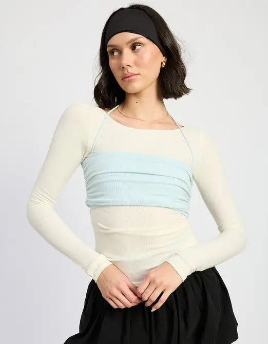 Woman wearing beige long sleeve top with light blue ruched bandeau and black skirt