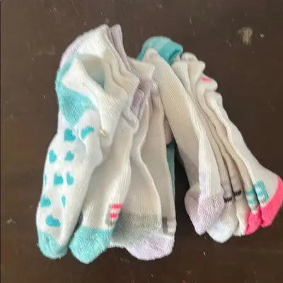 Pile of white girls’ ankle sports socks with colorful accents in blue pink purple and grey