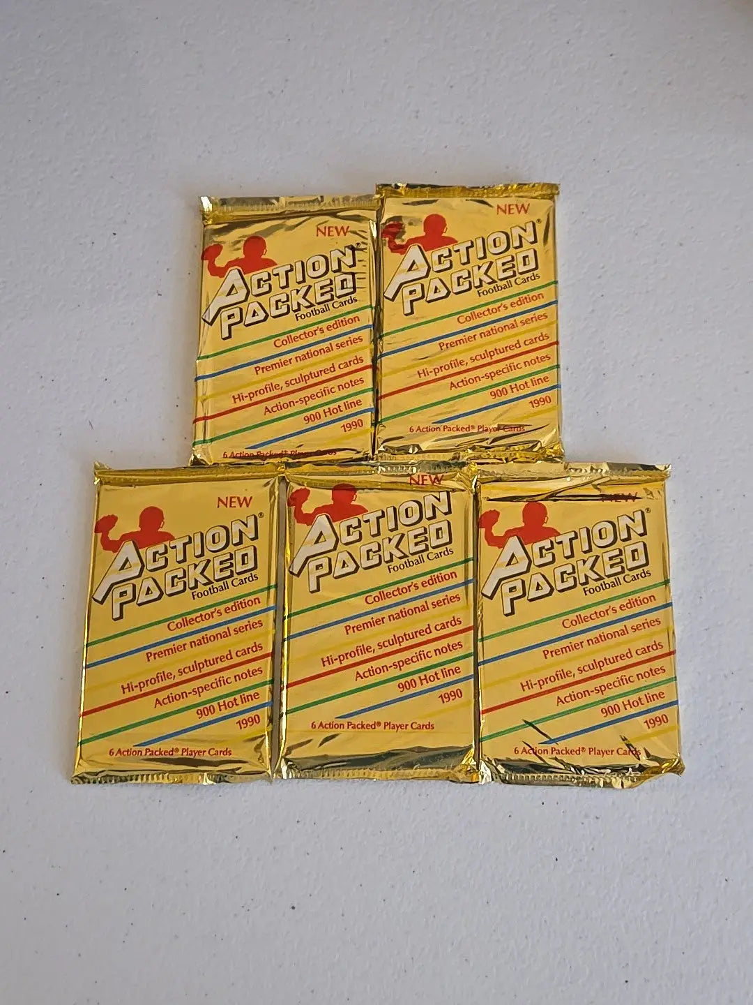 Five gold Action Packed football card packs from 1990 in a collectible lot