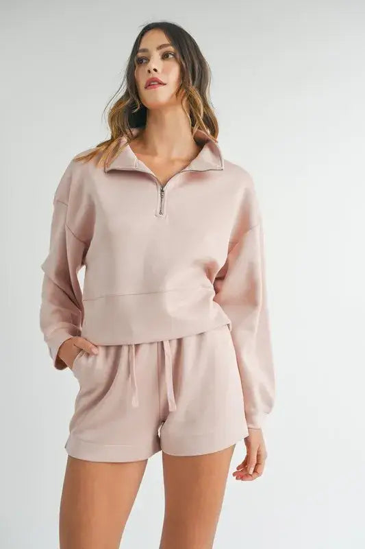 Woman modeling soft pink half zip sweatshirt and matching shorts from Mable Apparel