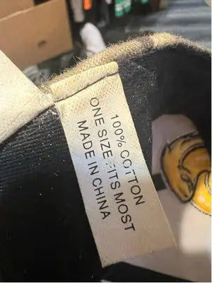 Clothing tag on dark fabric of Men’s The Game USM Golden Eagles Camo Yellow Baseball Cap