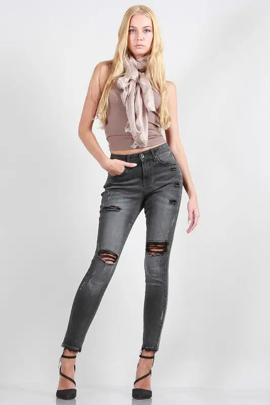 Full-length of woman in beige tank top, pink scarf, black rise skinny jeans, open-toe heels