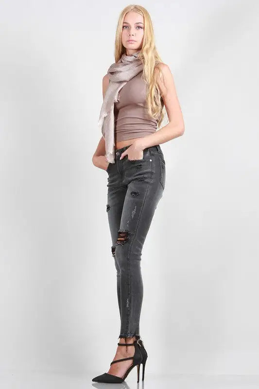 Woman modeling ripped black Mid Rise Skinny jeans with destroy detail
