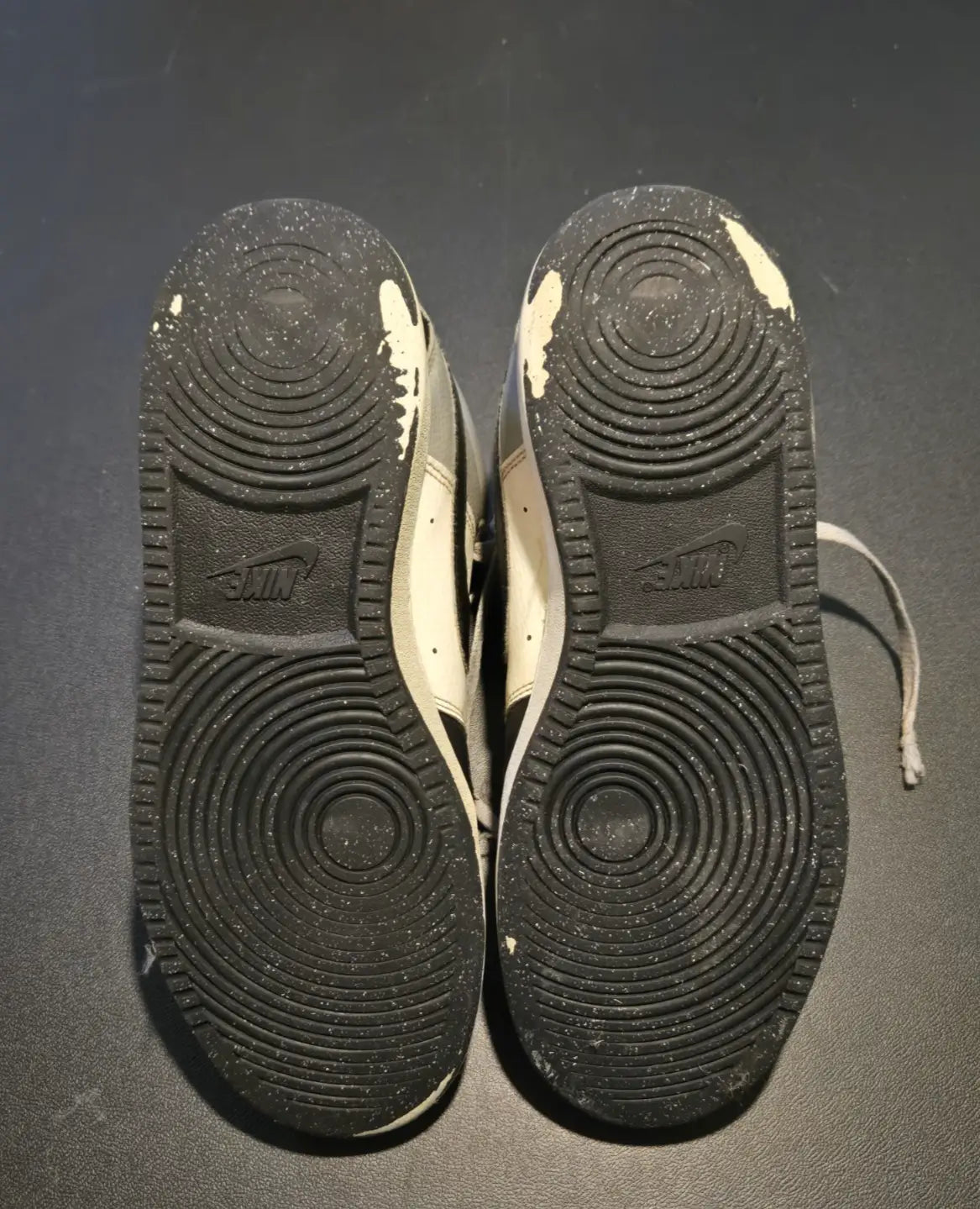Worn Nike Court Vision Mid Black and White sneakers with scuffs and dirt on soles