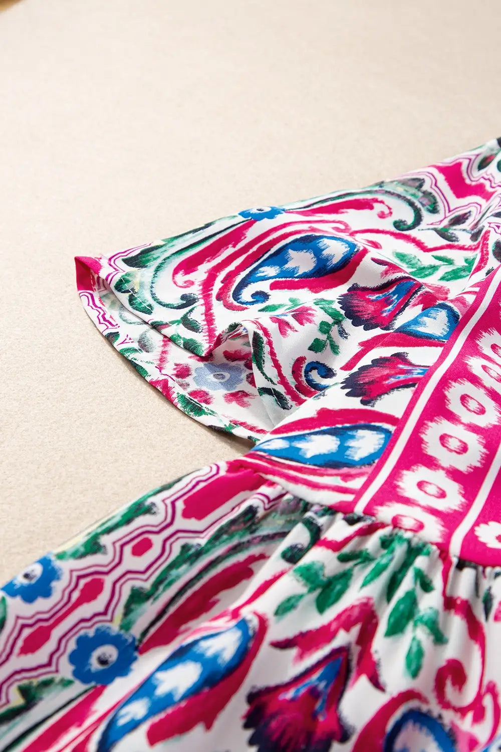 White fabric with vibrant pink blue and green paisley floral pattern on printed tie neck dress