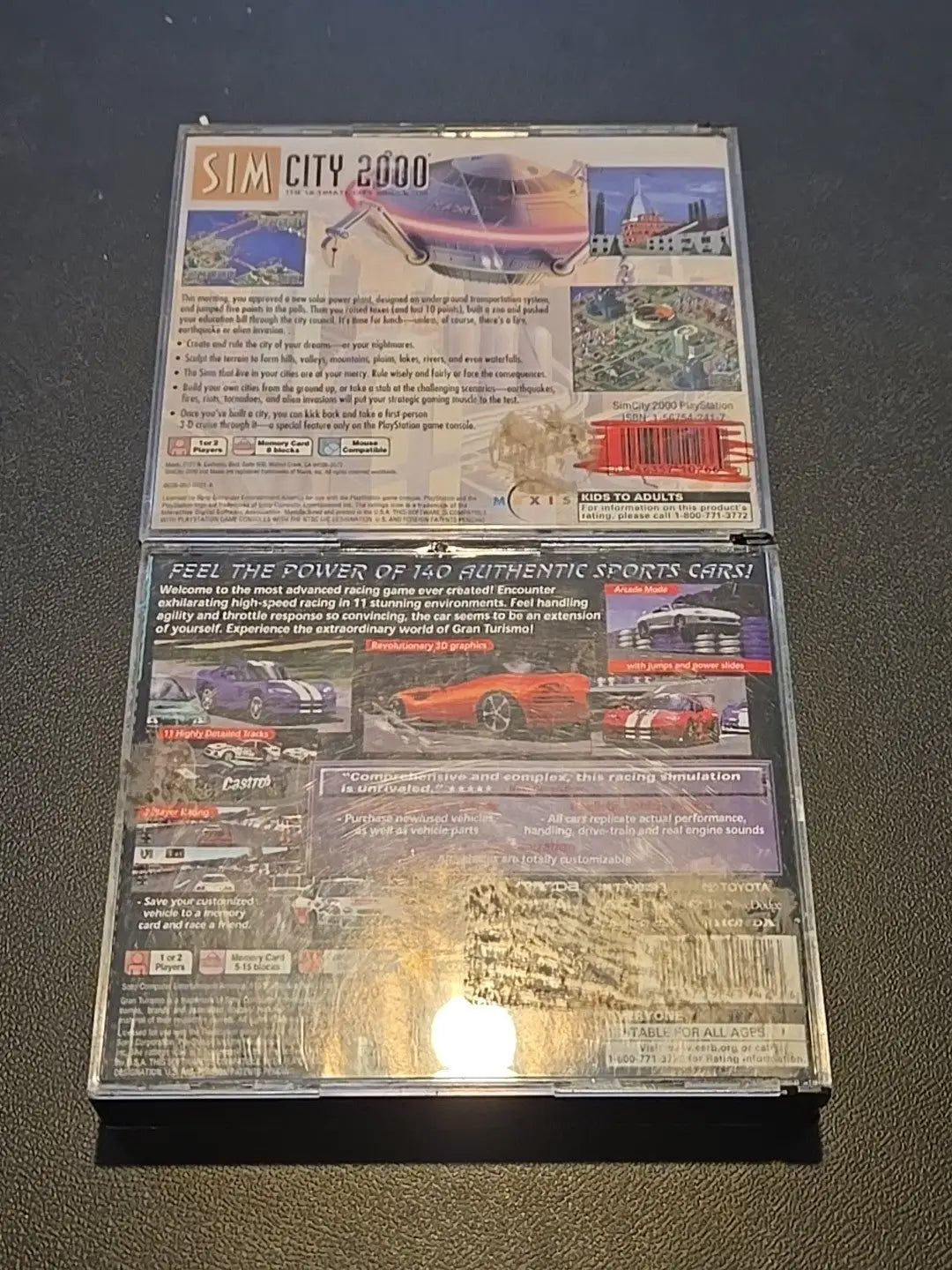 Two PlayStation game cases featuring Sim City 2000 and Gran Turismo Greatest Hits