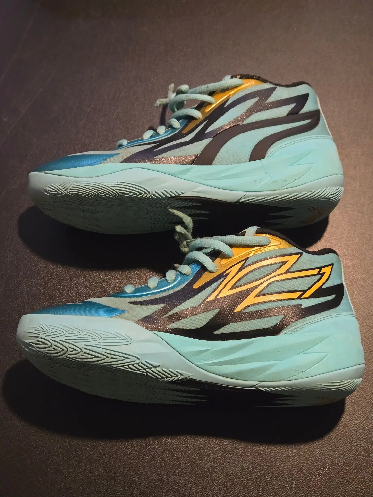 Aqua teal Puma basketball shoes for men with gold accents and jagged black blue designs