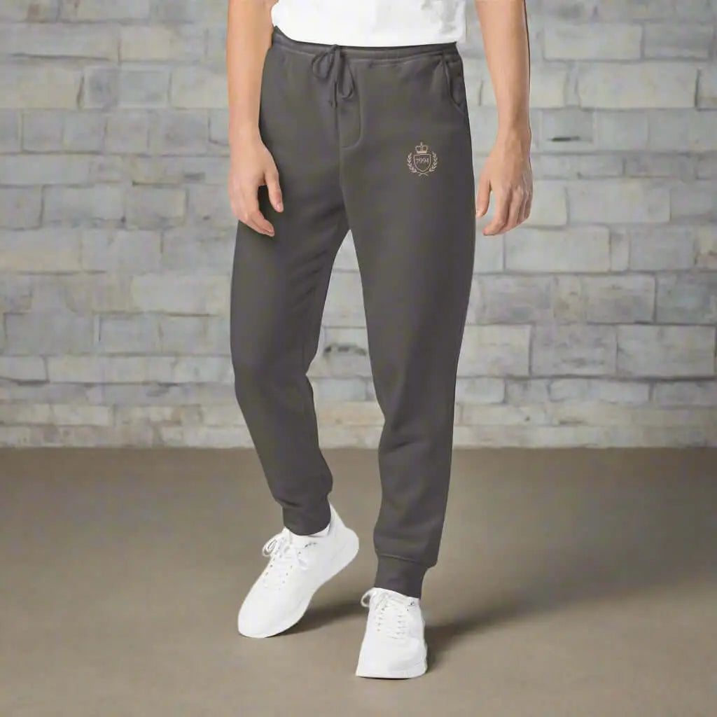 Dark gray Crested Luxe Joggers with gold emblem on left thigh for men and women