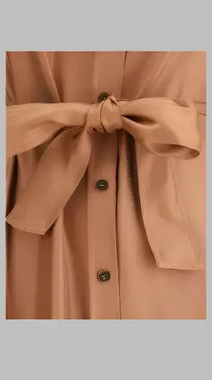 Close-up of a satin-like peach-colored Burnt Orange Long Shirt Dress with tied bow and buttons