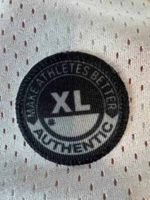 XL-sized black and white circular tag on white mesh fabric of Under Armour White Men’s Jersey