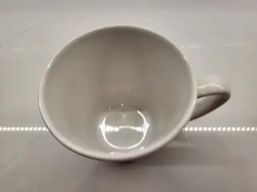 Empty white ceramic coffee mug featuring York Jets logo in green ceramic design