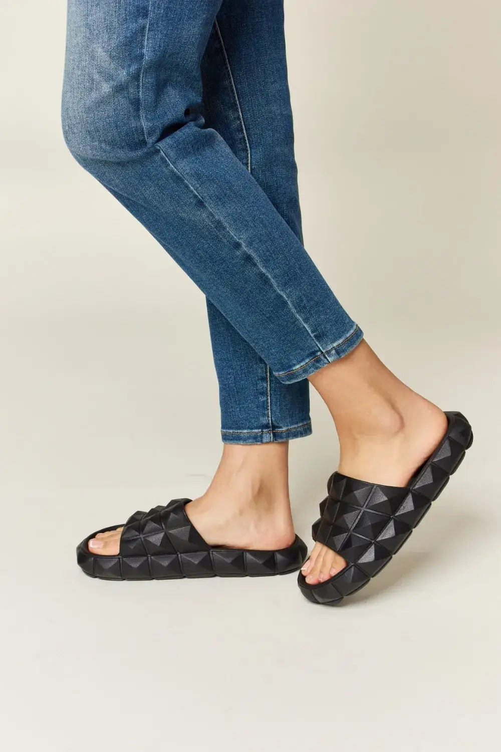 WILD DIVA Pyramid Stud Toe Band Footbed Sandals with black studded toe band and blue jeans