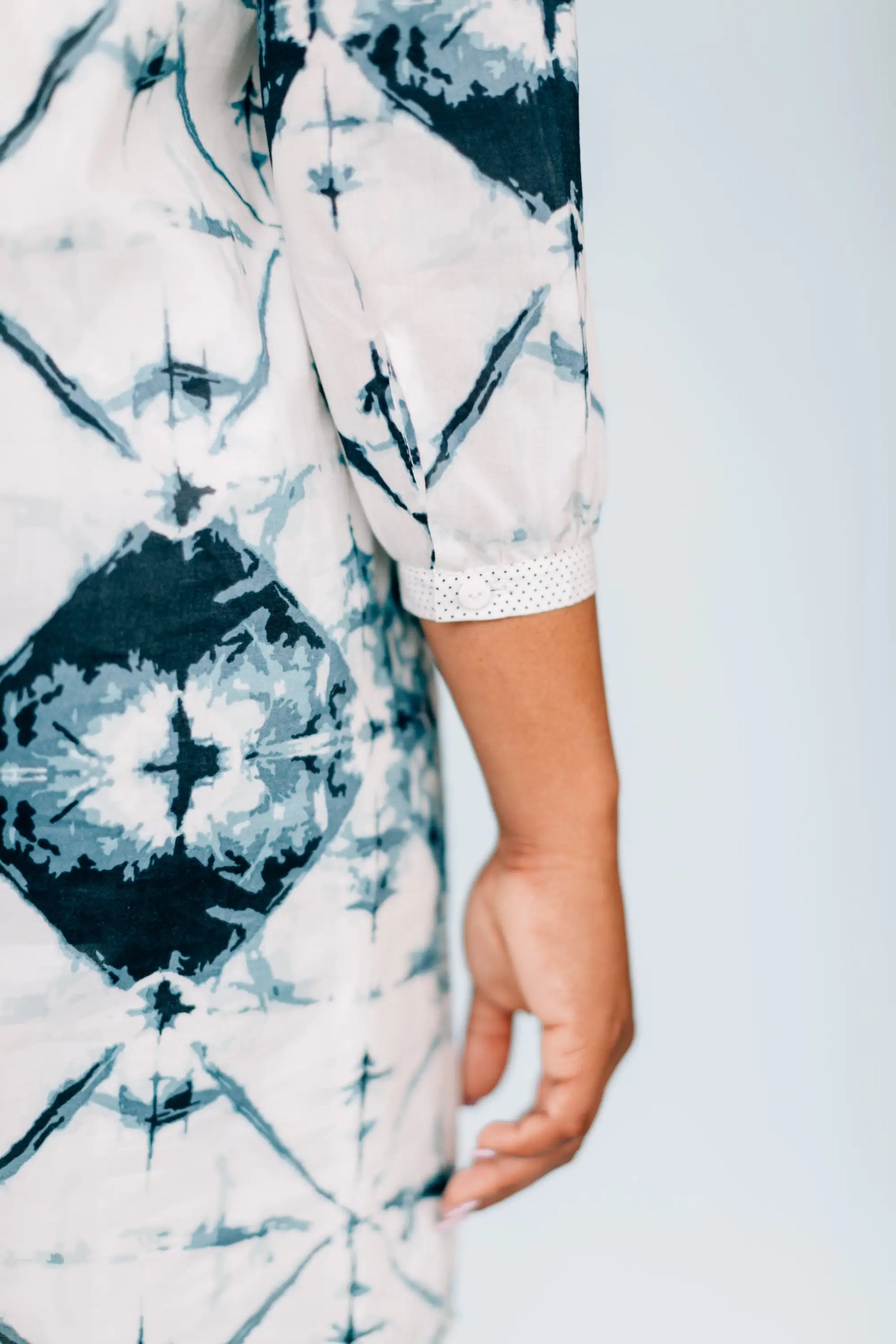 Woman wearing a woven slim fit dress with a tie-dye patterned shirt and dotted cuff