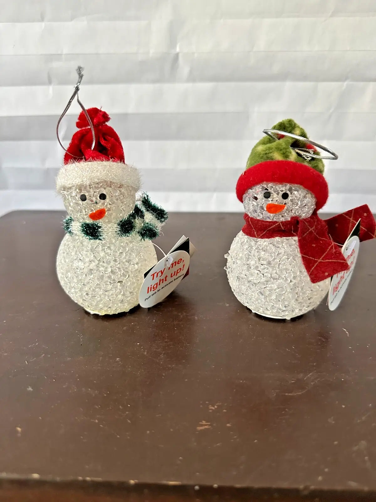 Two festive snowman ornaments with hats and scarves.