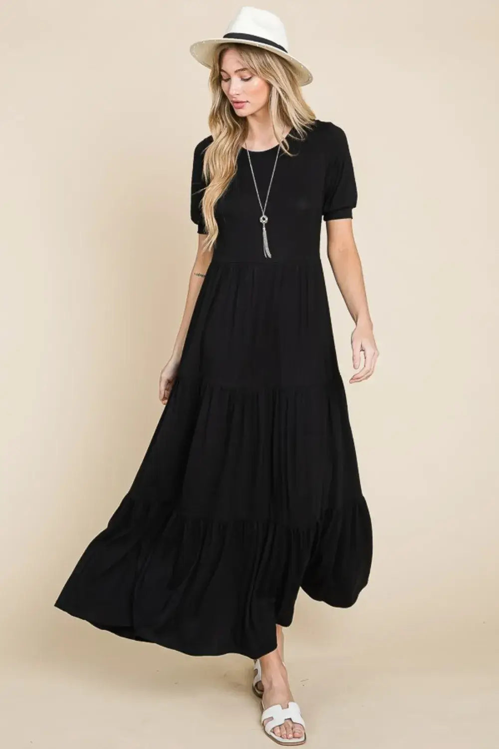 Black short-sleeved maxi dress with a pleated skirt and belt detail.