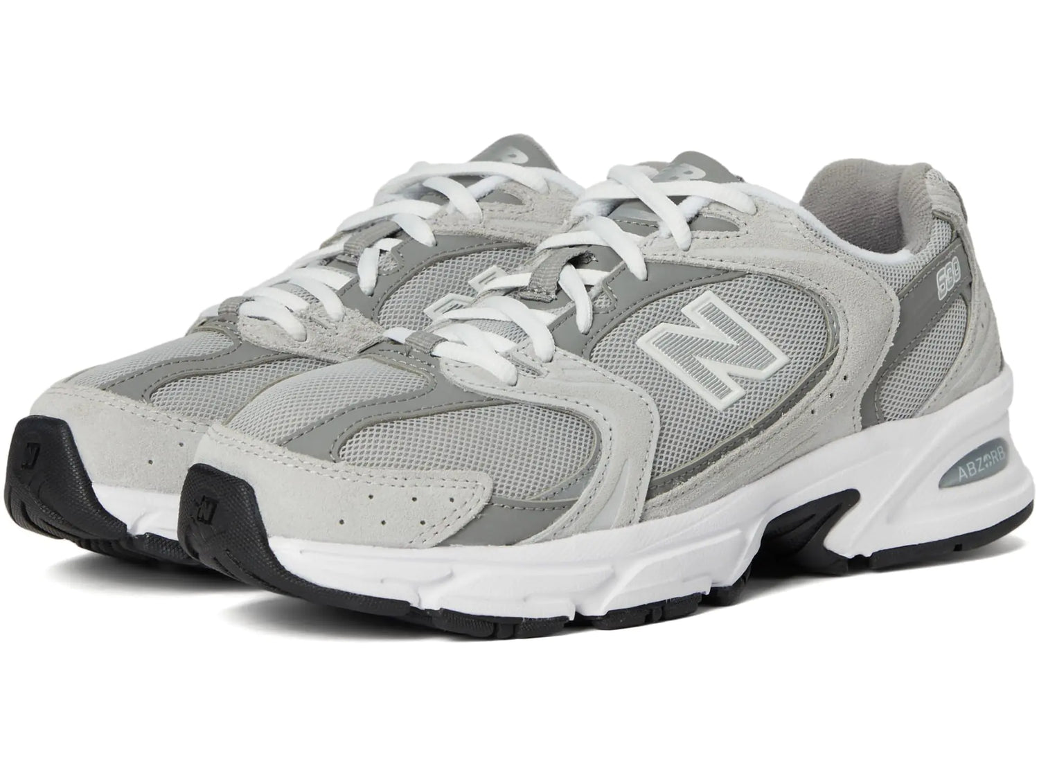 A pair of light gray and white New Balance athletic shoes with black soles.