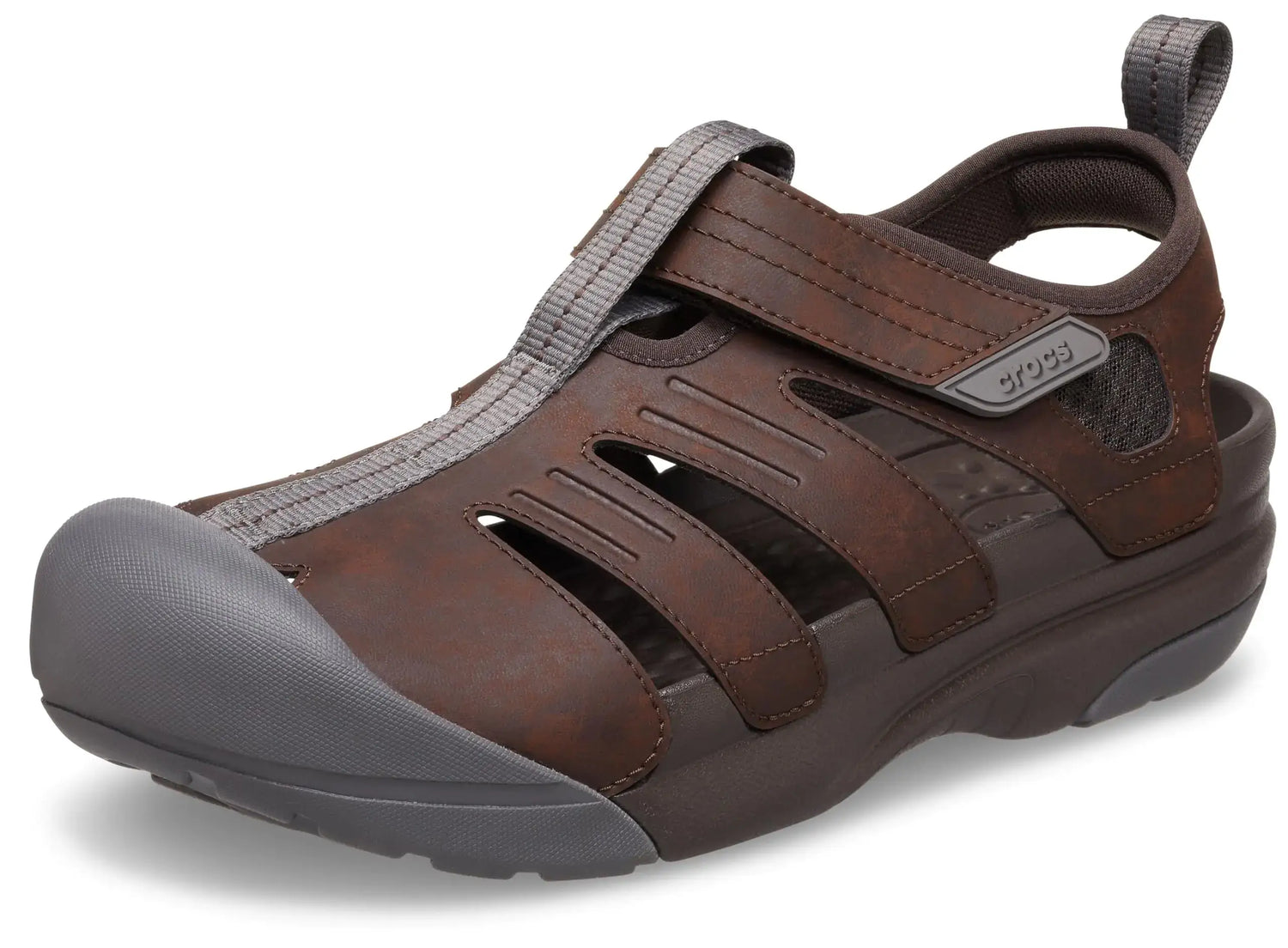 A brown closed-toe Crocs sandal with a grey protective toe cap and adjustable strap.