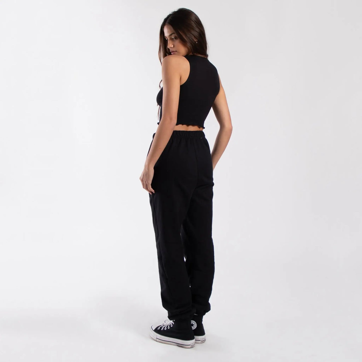 Black cropped lettuce trim muscle tank with high-waisted jogger pants and sneakers