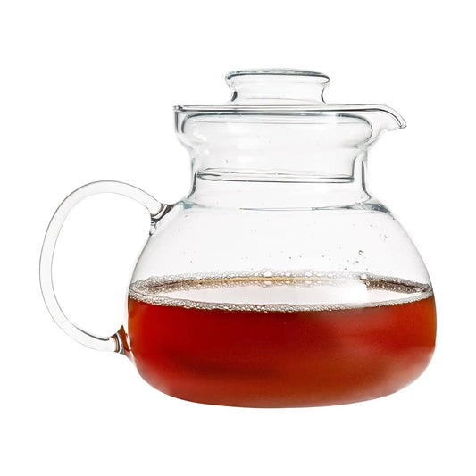 Glass teapot with handle and spout filled with amber tea, 1.5 quart glass teapot for stove top