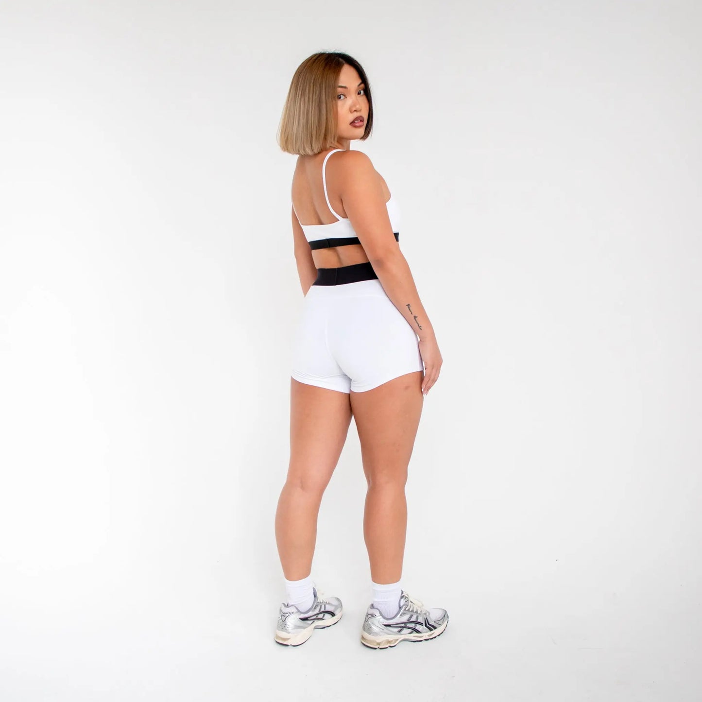 White athletic shorts with black waistband and silver sneakers from 1001BD info otlapparel