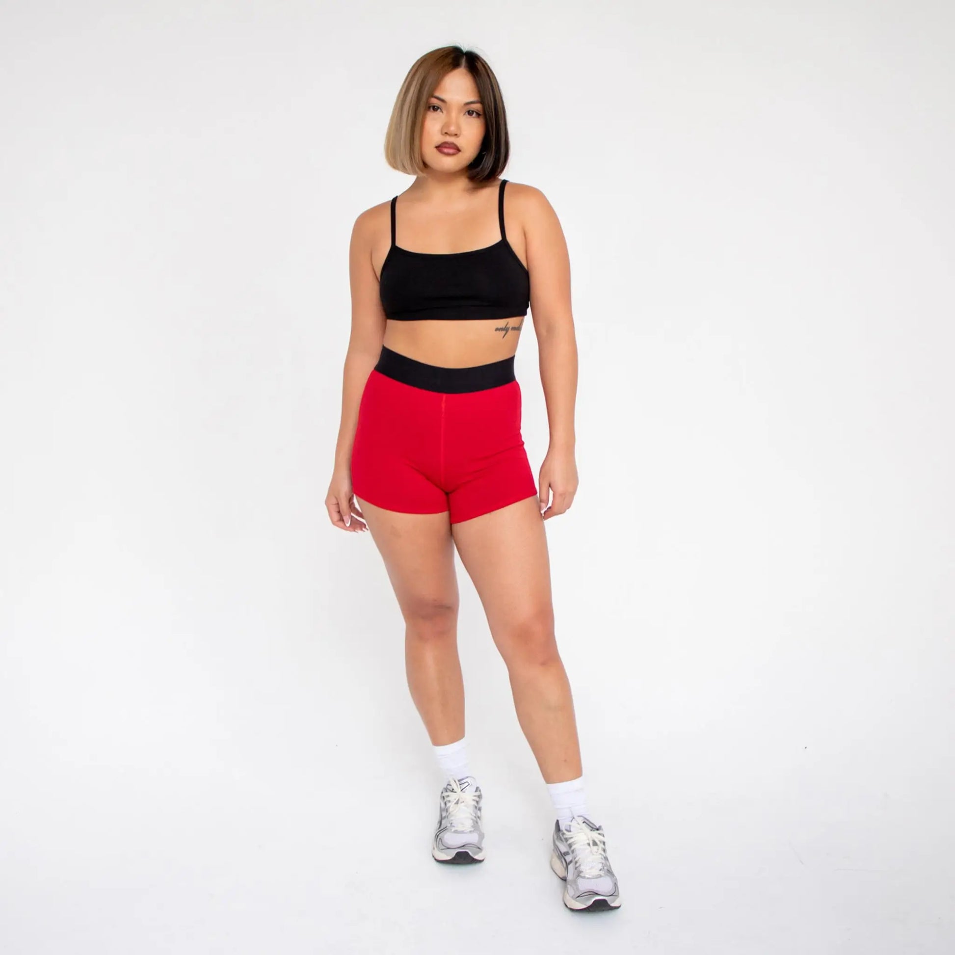 Red high-waisted athletic shorts with black straps and white socks from info otlapparel