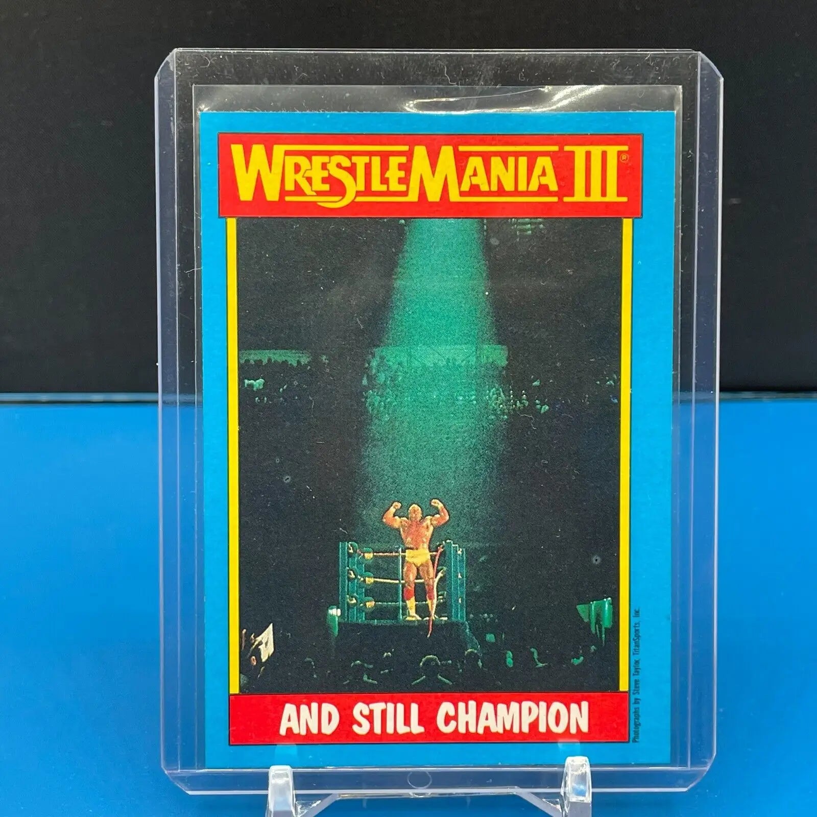 Vintage Topps trading card of Hulk Hogan celebrating at WrestleMania III under a spotlight