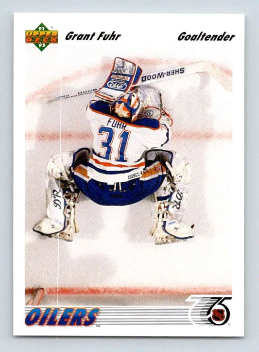 Hockey goalie Grant Fuhr in blue and white Edmonton Oilers jersey making a save on hockey card