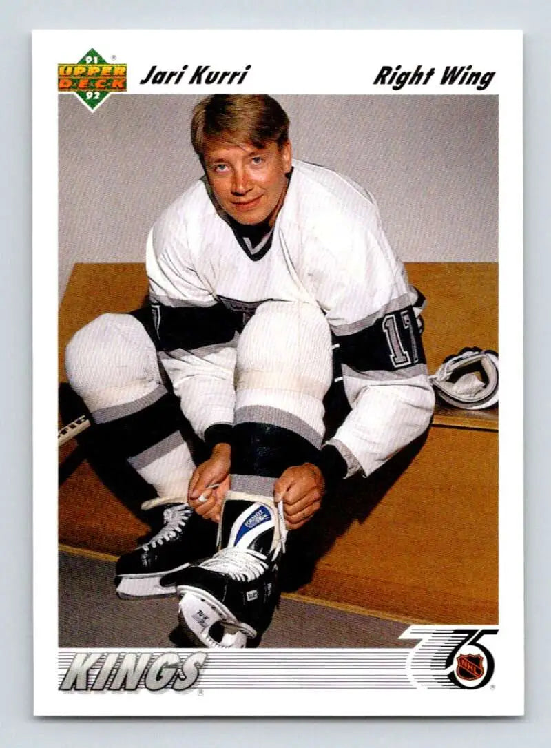 Hockey player in a white Kings jersey tying skates for Jari Kurri Upper Deck card