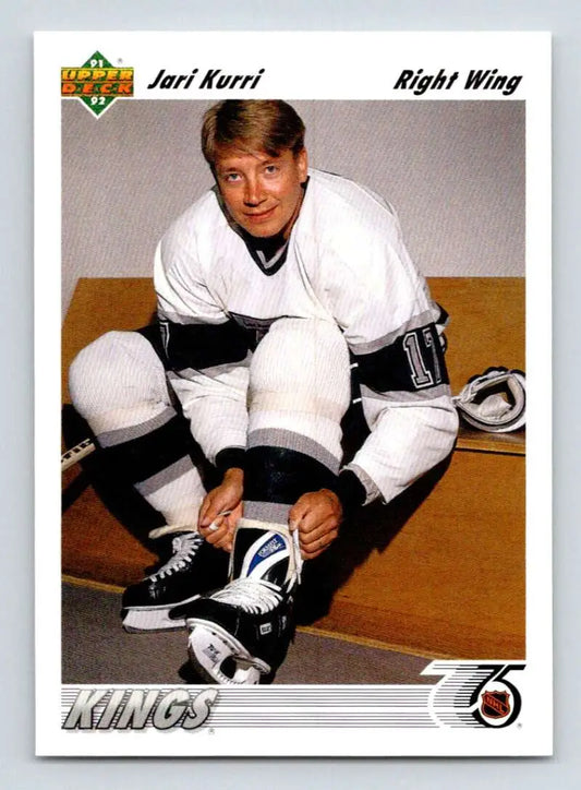 Hockey player in a white Kings jersey tying skates for Jari Kurri Upper Deck card