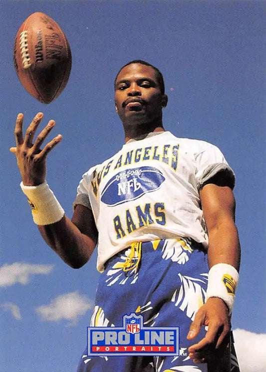 Football player in Los Angeles Rams shirt tossing football near Willie Anderson card